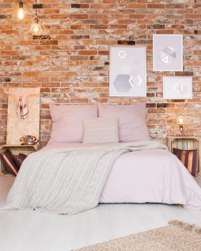 Cozy bedroom with double bed, ethnic commode and brick wall