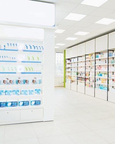 Empty spacious modern new white drugstore pharmacy chemist`s store with shelves full of medicines, pills, vitamins, painkillers, antibiotics without visitors