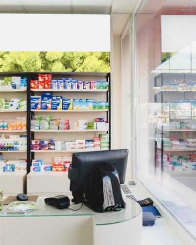 Empty spacious new modern cash point desk without visitors clients staff at pharmacy drugstore chemist`s store with shelves full of medicines
