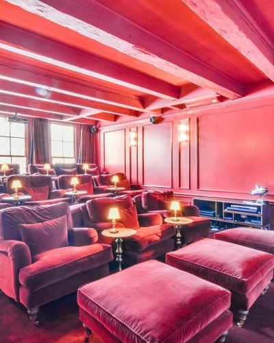 Pink colored luxury room with red velvet armchairs in cinema hall of mansion house