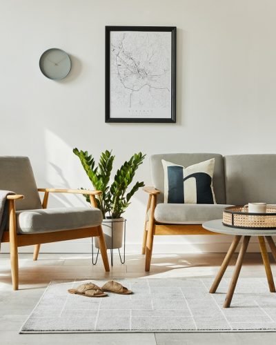 Modern retro concept of home interior with design sofa, armchair, coffee table, plants, mock up poster map, carpet and personal accessoreis. Stylish home decor of living room.